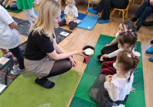 Nauczycielka podaje dzieciom pojemnik z punktami.