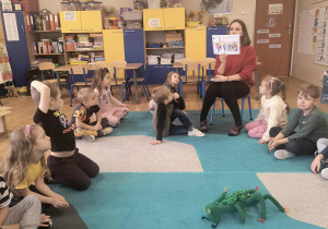 Pani psycholog czyta dzieciom opowiadanie o przyjaźni, a dzieci siedzą w kole.