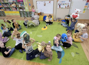 Dzieci siedzą w kręgu i trzymają swoje pluszowe zabawki.