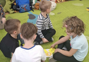 Dzieci siedzą na dywanie w kilkuosobowych grupach i układają puzzle.