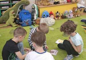Dzieci siedzą na dywanie w kilkuosobowych grupach i układają puzzle.
