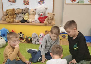 Dzieci siedzą na dywanie w kilkuosobowych grupach i układają puzzle.