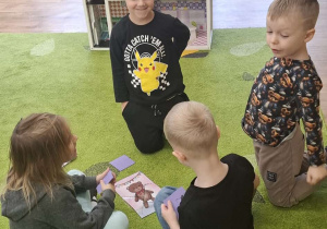 Dzieci siedzą na dywanie w kilkuosobowych grupach i układają puzzle.