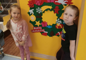 Dwoje dzieci dekoruje wieniec bożonarodzeniowy