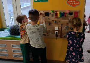 Dzieci bawią się elementami tablicy sensorycznej