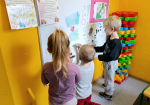 Dzieci malują na tablicy mazakami suchościeralnymi
