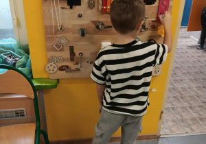 Chłopiec bawi się elementami tablicy sensorycznej