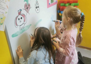 Dziewczynki z grupy starszaków rysują na tablicy według własnego pomysłu