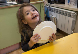 Dziewczynka zlizuje Nutellę z talerzyka.