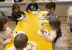 Dzieci przy stoliku komponują kanapki w kształcie misia.