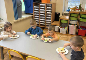 Dzieci przy stoliku komponują kanapki w kształcie misia.