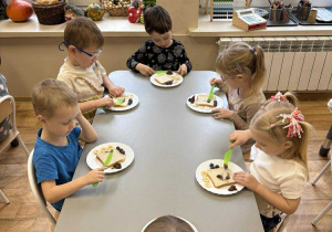 Dzieci przy stoliku komponują kanapki w kształcie misia.