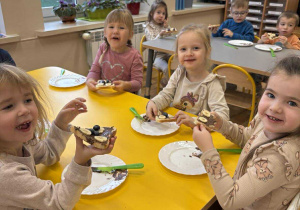 Dzieci jedzą zrobione przez siebie kanapki.