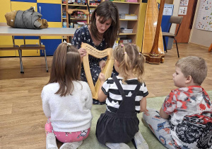 Harfistka prezentuje dzieciom instrument.