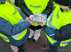 Troje dzieci trzyma świąteczną kartkę na dłoniach.