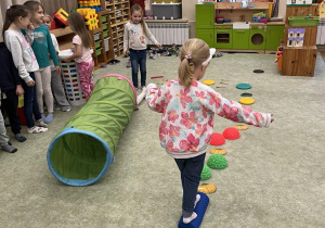 Dzieci pokonują jesienny tor przeszkód.