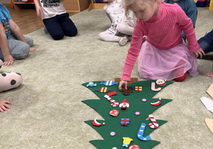 Dzieci ozdabiają choinkę według wskazówek.