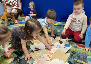 Maluszki ozdabiają choinkę według wskazówek.