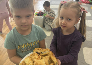 Dwoje dzieci trzyma talerz z upieczonymi smakołykami.