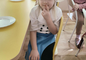 Dziewczynka siedzi przy stoliku w oczekiwaniu na ciasteczko.