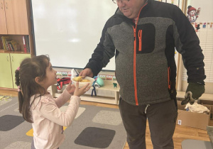 Dziewczynka częstuje pana konserwatora swoimi wypiekami.