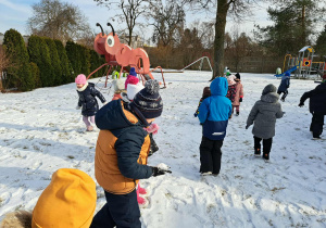 Grupa dzieci lepi kulki ze śniegu.