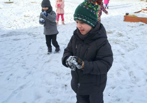 Grupa dzieci lepi kulki ze śniegu.