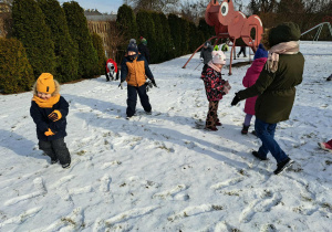 Grupa dzieci bawi się na śniegu.
