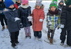Pięcioro dzieci pokazuje na dłoniach ulepione kulki śniegowe.