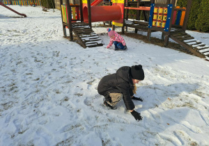 Grupa dzieci lepi kulki ze śniegu.