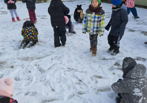 Grupa dzieci bawi się na śniegu.