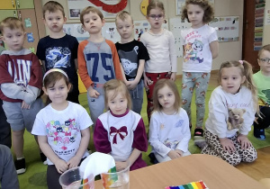 Dzieci stoją przy stoliku i obserwują eksperyment z "tęczą".