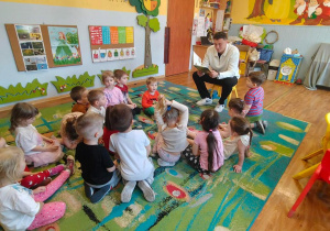 Dzieci słuchają radnego, który czyta wiersze.