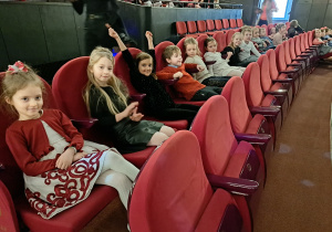 Grupa dzieci siedzi na widowni w teatrze.