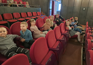 Grupa dzieci siedzi na widowni w teatrze.