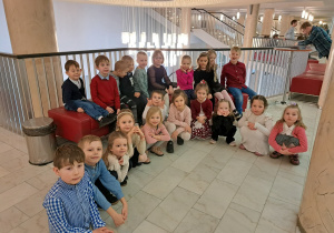 3 Grupa dzieci (część siedzi, część kuca) na korytarzu teatru przed wejściem na widownię