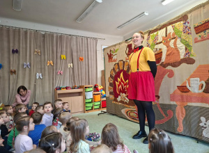 Aktorka teatralna na tle scenografii.