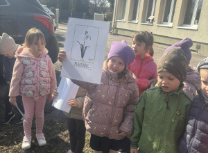 Dziewczynka pokazuje obrazek z kwiatkiem, który znalazła w ogrodzie