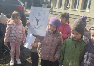 Dziewdzynka pokazuje ilustrację z kwiatkiem, który odnalazła w ogrodzie.