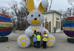 Dzieci prezentujące dyplom na tle dużego, wielkanocnego zajączka.