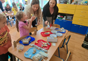 Dzieci i rodzice wykonują wielkanocne ozdoby.