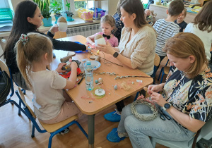 Dzieci i rodzice wykonują wielkanocne ozdoby.
