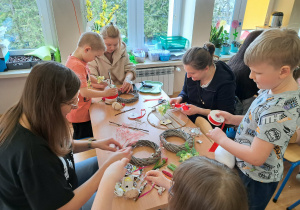 Dzieci i rodzice wykonują wielkanocne ozdoby.