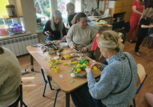 Dzieci i rodzice wykonują wielkanocne ozdoby.