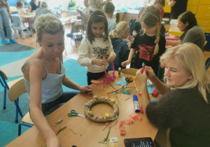 Dzieci i rodzice wykonują wielkanocne ozdoby.