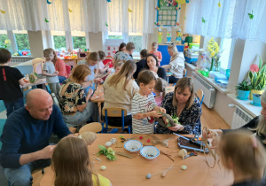 Dzieci i rodzice wykonują wielkanocne ozdoby.