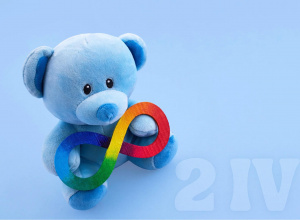 Pluszowy, błękitny miś trzymający znak nieskończoności w kolorach tęczy.