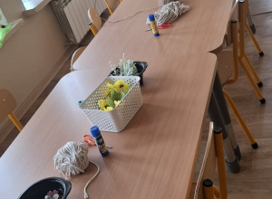 Stoły, na których przygotowane są materiały i ozdoby potrzebne do wykonania wianków wielkanocnych.