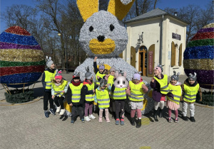 Dzieci pozują do zdjęcia na tle wielkoformatowych, wielkanocnych dekoracji.