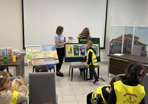 Chłopiec przyporządkowuje ilustracje odpadów do odpowiednich miejsc na planszy.